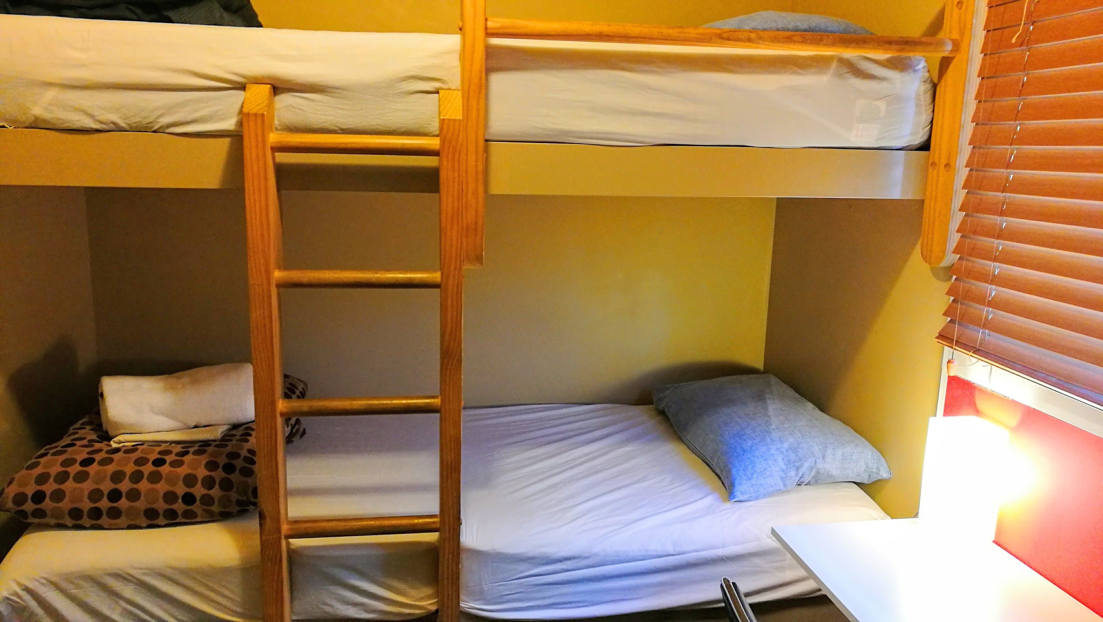 A bunk bed with a ladder, two pillows, and a small table.
