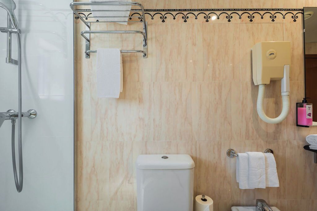 A bathroom with a toilet, a shower, and a towel rack.