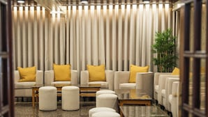 Un espace de détente moderne, avec des canapés et des poufs disposés autour d’une table basse centrale.