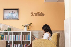 Un salón acogedor con una estantería, un retrato familiar enmarcado y un letrero decorativo en la pared.