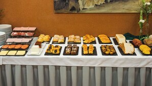 Une table de buffet proposant une variété de pâtisseries, de fromages et de charcuteries.