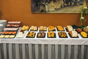 Una mesa de buffet con diversos pasteles, quesos y embutidos.