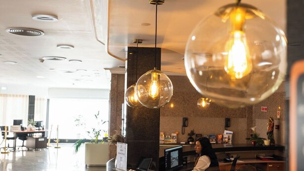 Un espace d’accueil moderne, avec un luminaire en forme de dôme de verre, un comptoir d’accueil et un écran d’ordinateur.