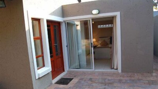 Un pequeño hotel de una sola habitación con puerta de vidrio corredera, una puerta roja y un patio con baldosas.