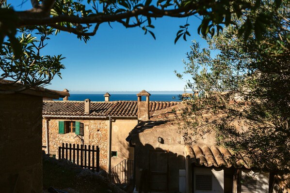 A rustic building with a stone facade, a tiled roof, and a view of the sea.