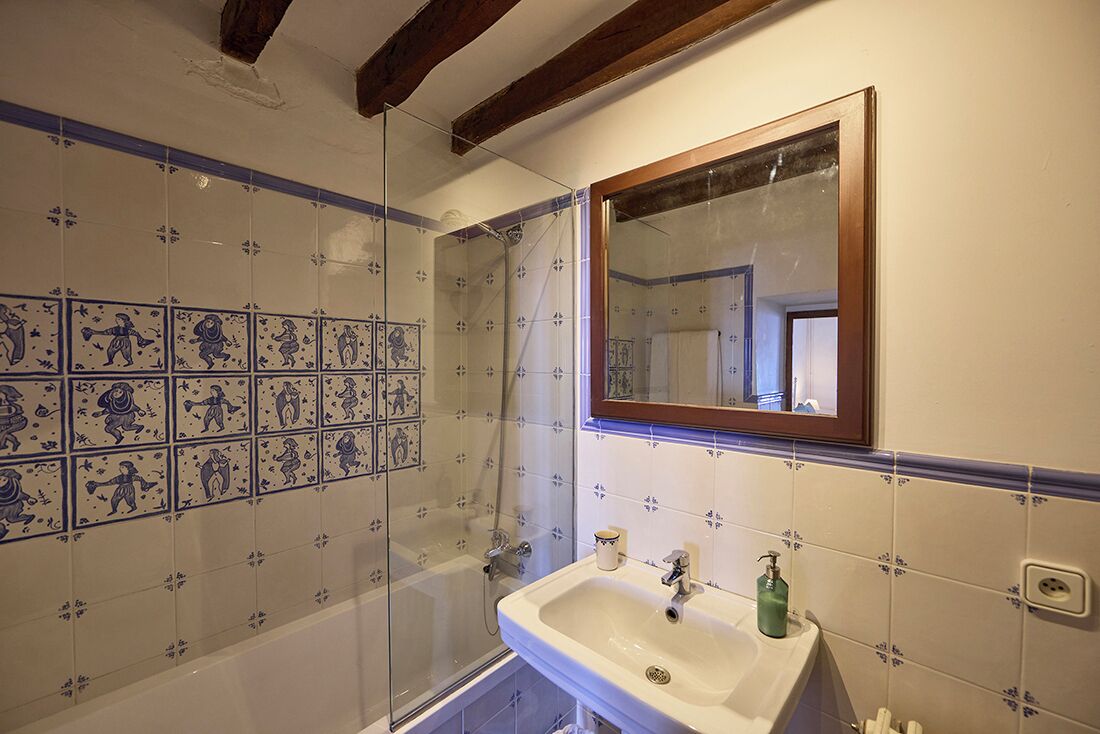A bathroom with a shower, a sink, and decorative tiles.