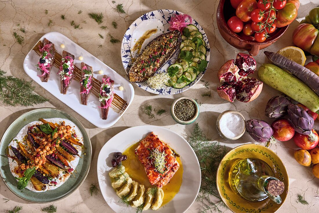 Diversos platos con pescado, verduras y frutas, sugiriendo una comida.