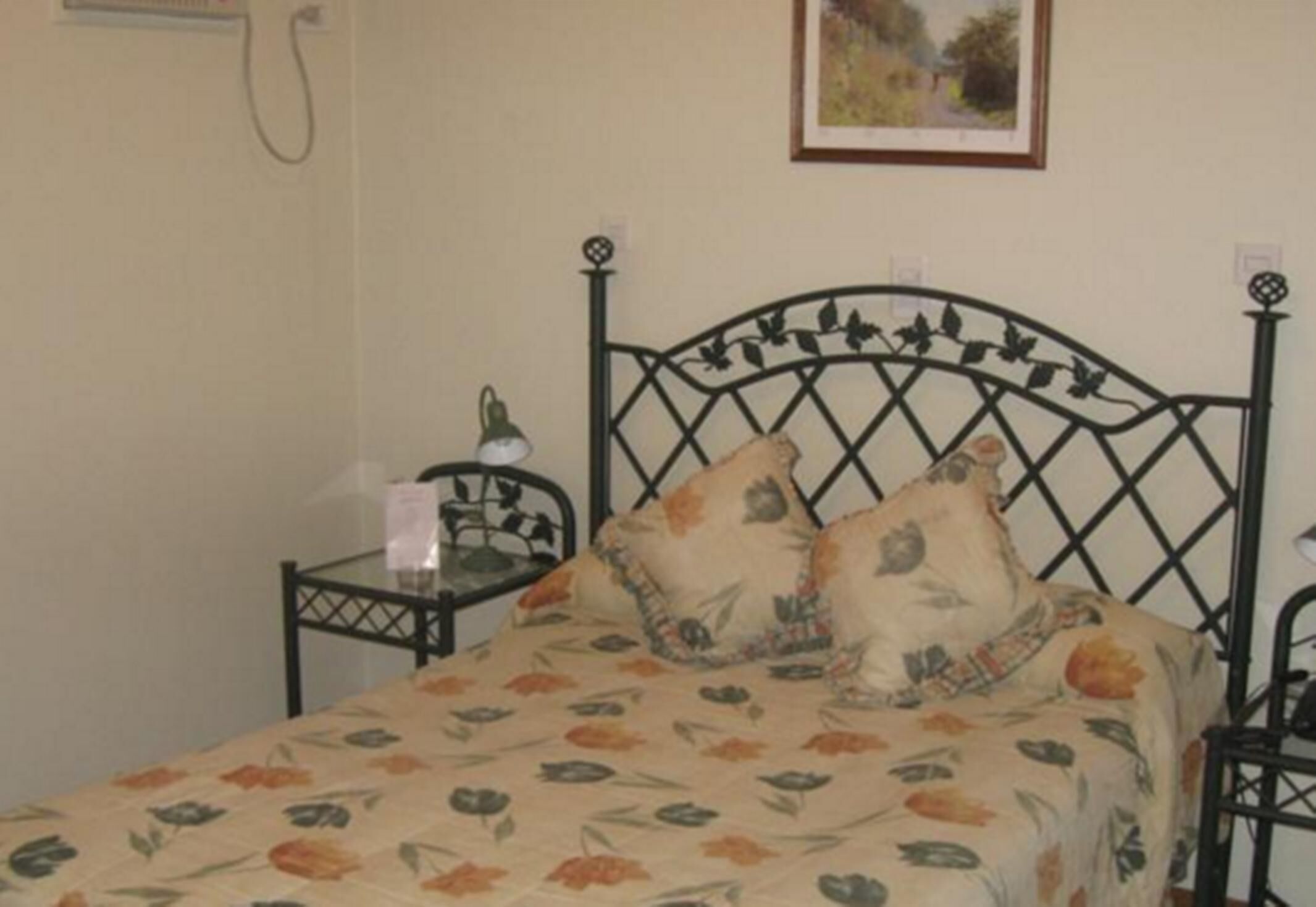 Una cama con una colcha estampada, una mesita de noche con lámpara y una silla.
