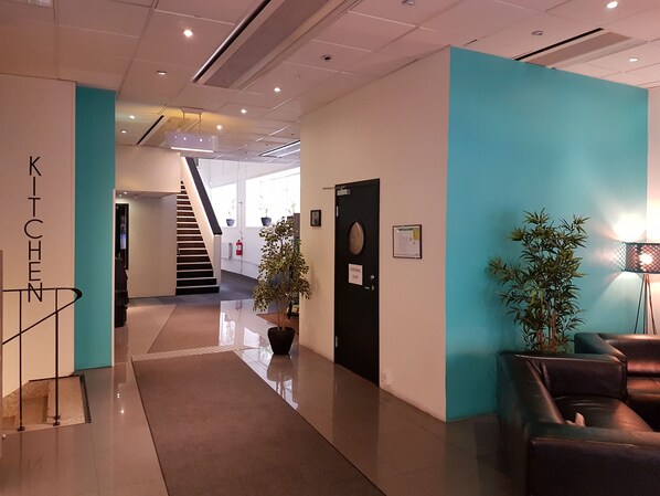 A modern hotel lobby with a staircase, a reception desk, and a seating area.