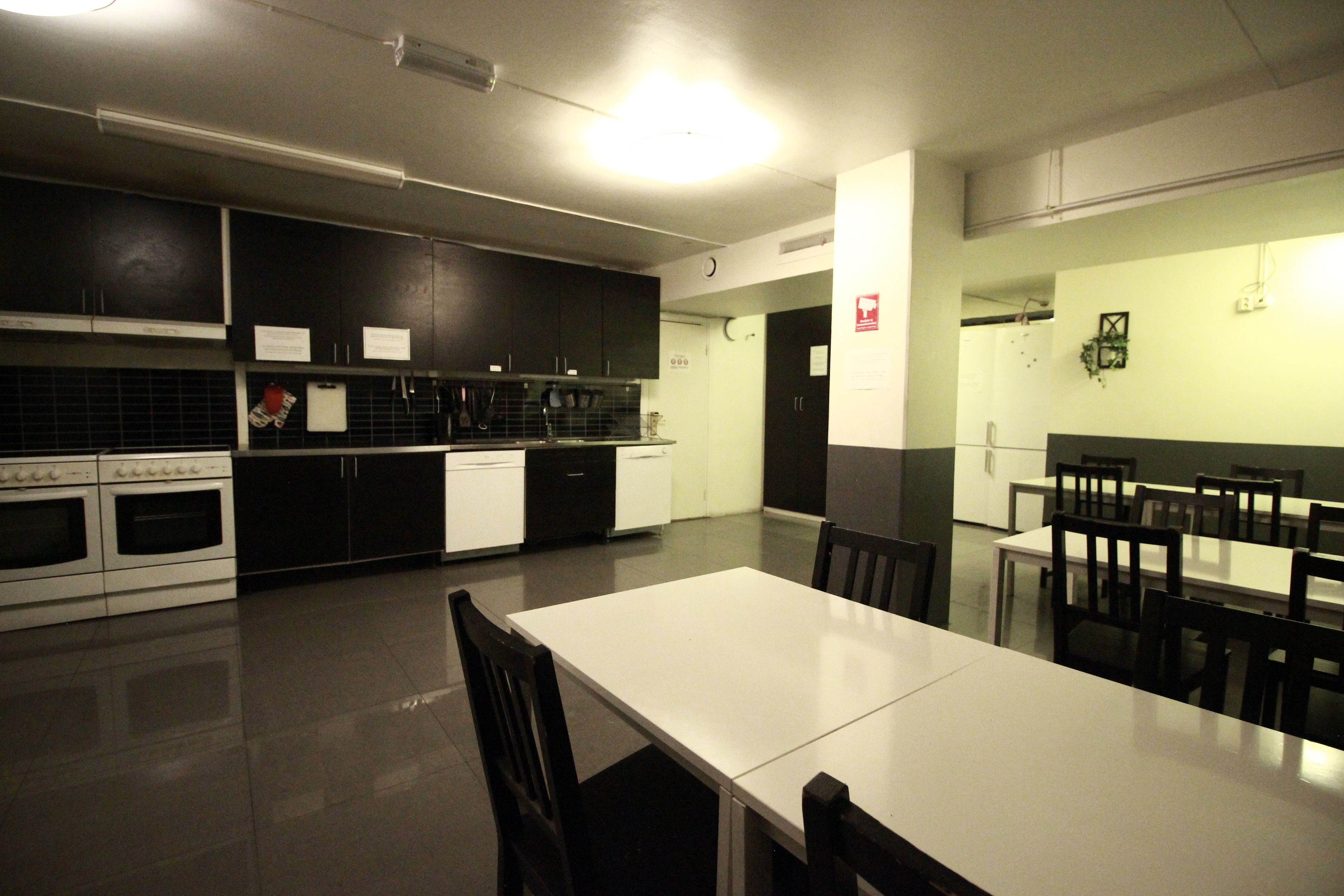 A modern kitchen with dark cabinets, white appliances, and a large dining table with chairs.