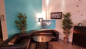 A living room with a sectional sofa, a coffee table, and two potted plants. - Hotell Centralstation (Uppsala)