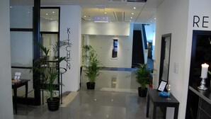 A modern hotel lobby with a reception desk, potted plants, and a sign reading "BREAKEFAST". - Hotell Centralstation (Uppsala)