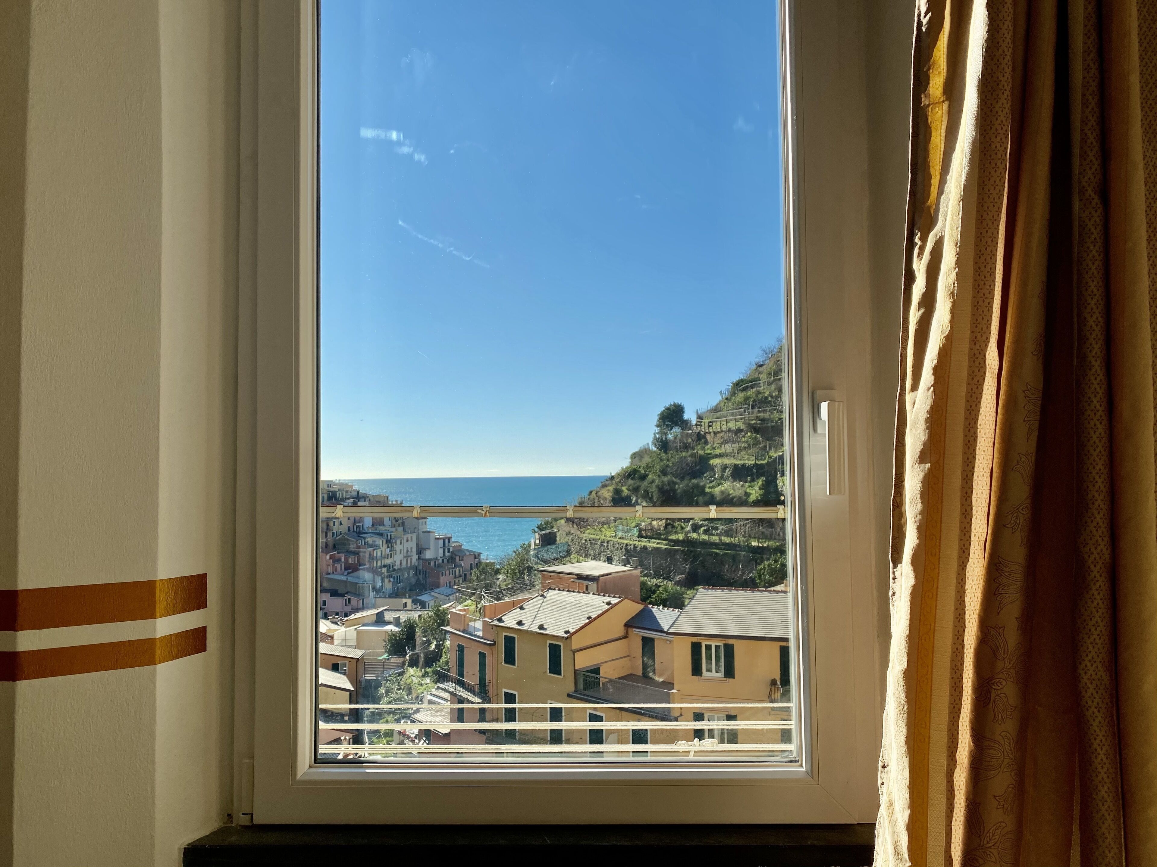 A window with a view of a coastal town, buildings, and a bridge.