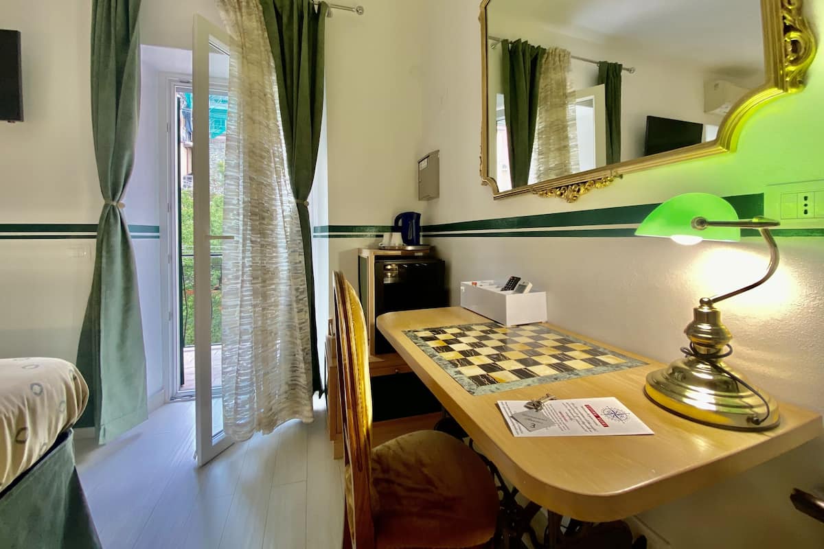 A room with a bed, a desk with a chessboard, a mirror, and a lamp.