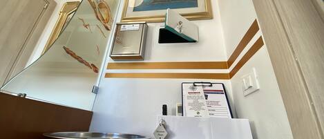Un comptoir d’accueil orné d’un tableau encadré représentant un paysage côtier, une boîte pour recueillir les paiements et un classeur contenant une carte et des informations.