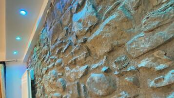 A textured stone wall with a modern ceiling design featuring recessed lighting.