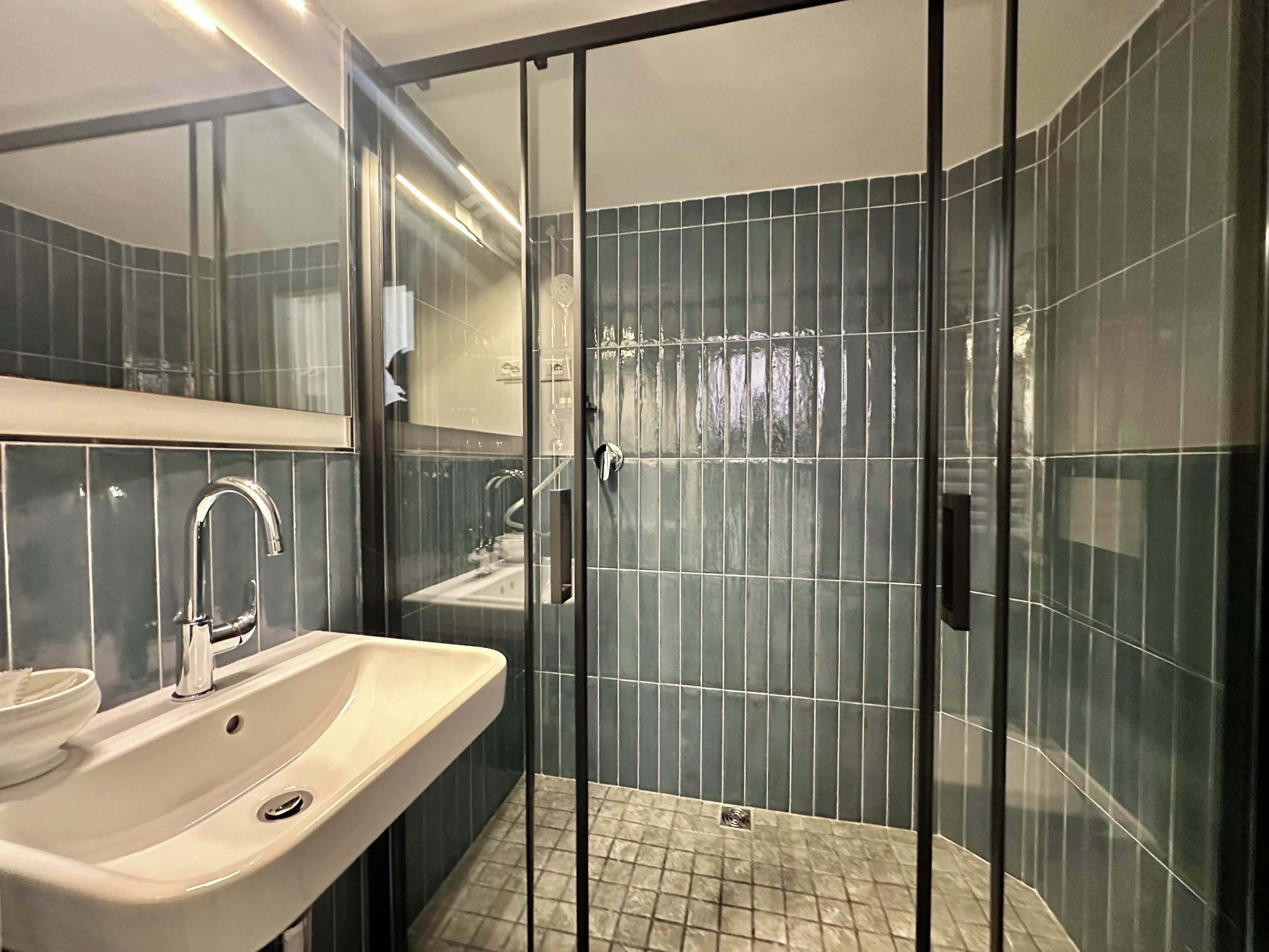 Een moderne badkamer met een glazen douchecabine, een wastafel en een spiegel.