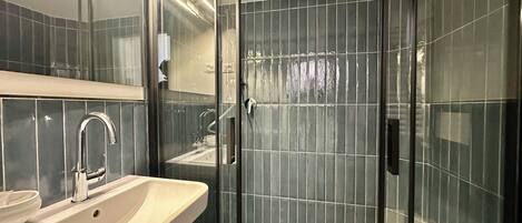 Een moderne badkamer met een glazen douchecabine, een wastafel en een spiegel.