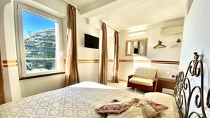 Ett hotellrum med en stor säng, en stol, en spegel och ett fönster med gardiner.