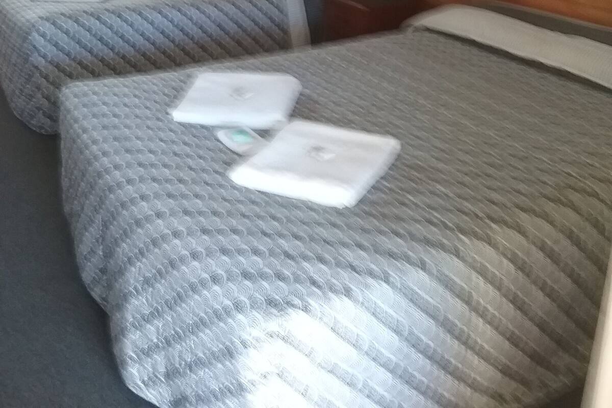 Une chambre d’hôtel avec deux lits, une tête de lit en bois et une petite table.