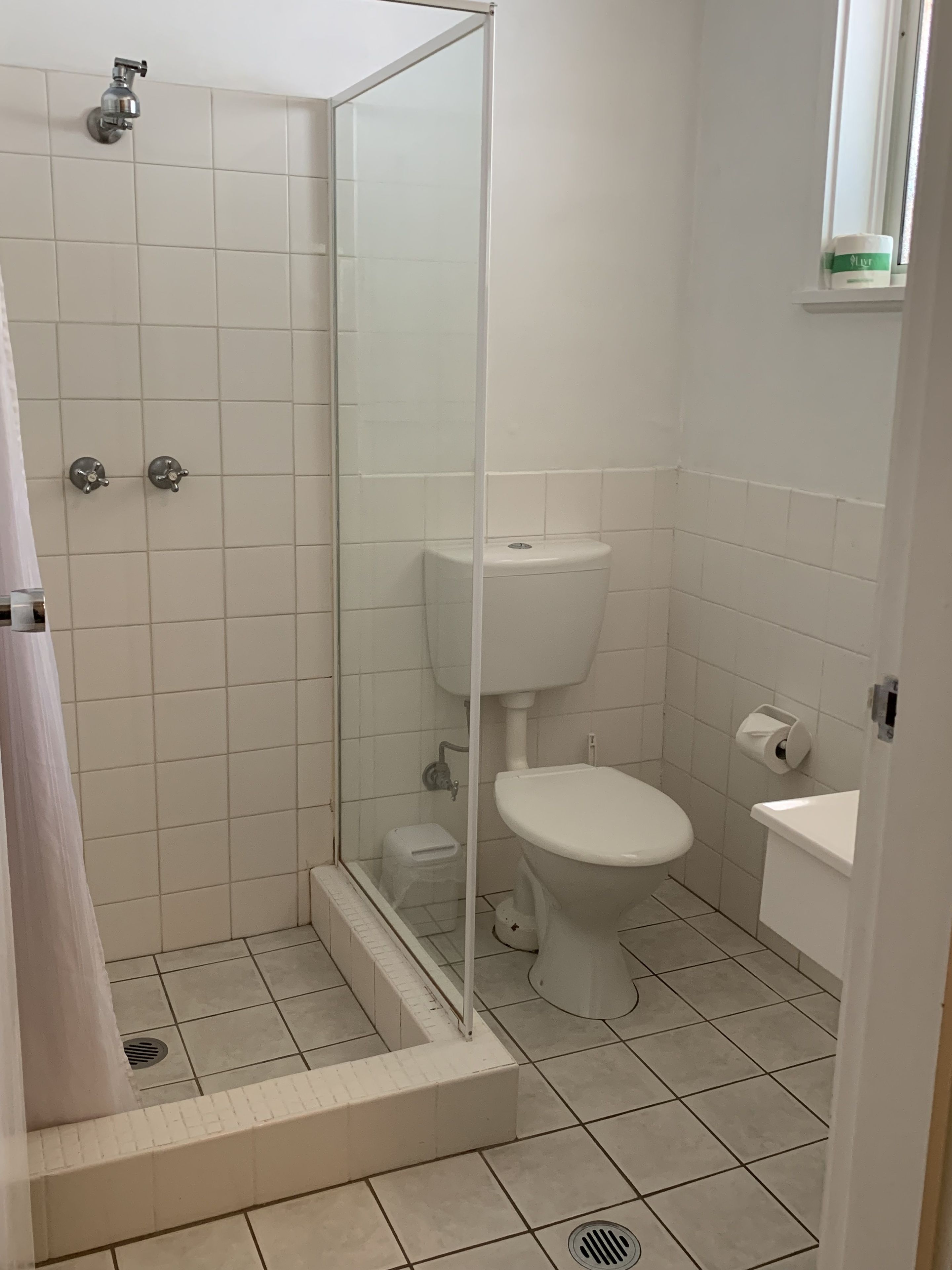 Une salle de bain avec une douche à parois de verre, des toilettes et un lavabo.