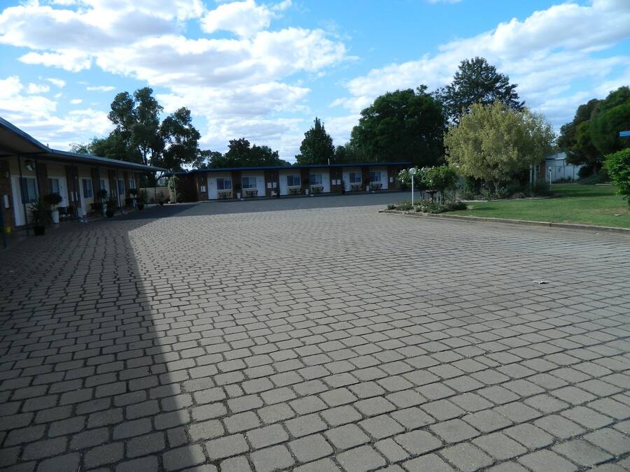 Une cour spacieuse, dotée d’un sol pavé et entourée d’immeubles comportant de nombreuses fenêtres et portes, dont certains offrent des espaces de détente en plein air.