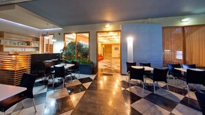 Un moderno vestíbulo de hotel con piso a cuadros, zonas de estar y un mostrador de recepción.