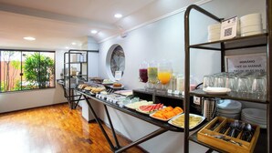 Un bufé de desayuno con diversos alimentos y bebidas, una estación de café, y vistas al exterior.