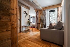 A cozy living room with a wooden floor, a sofa, a coffee table, and a staircase leading to another level.