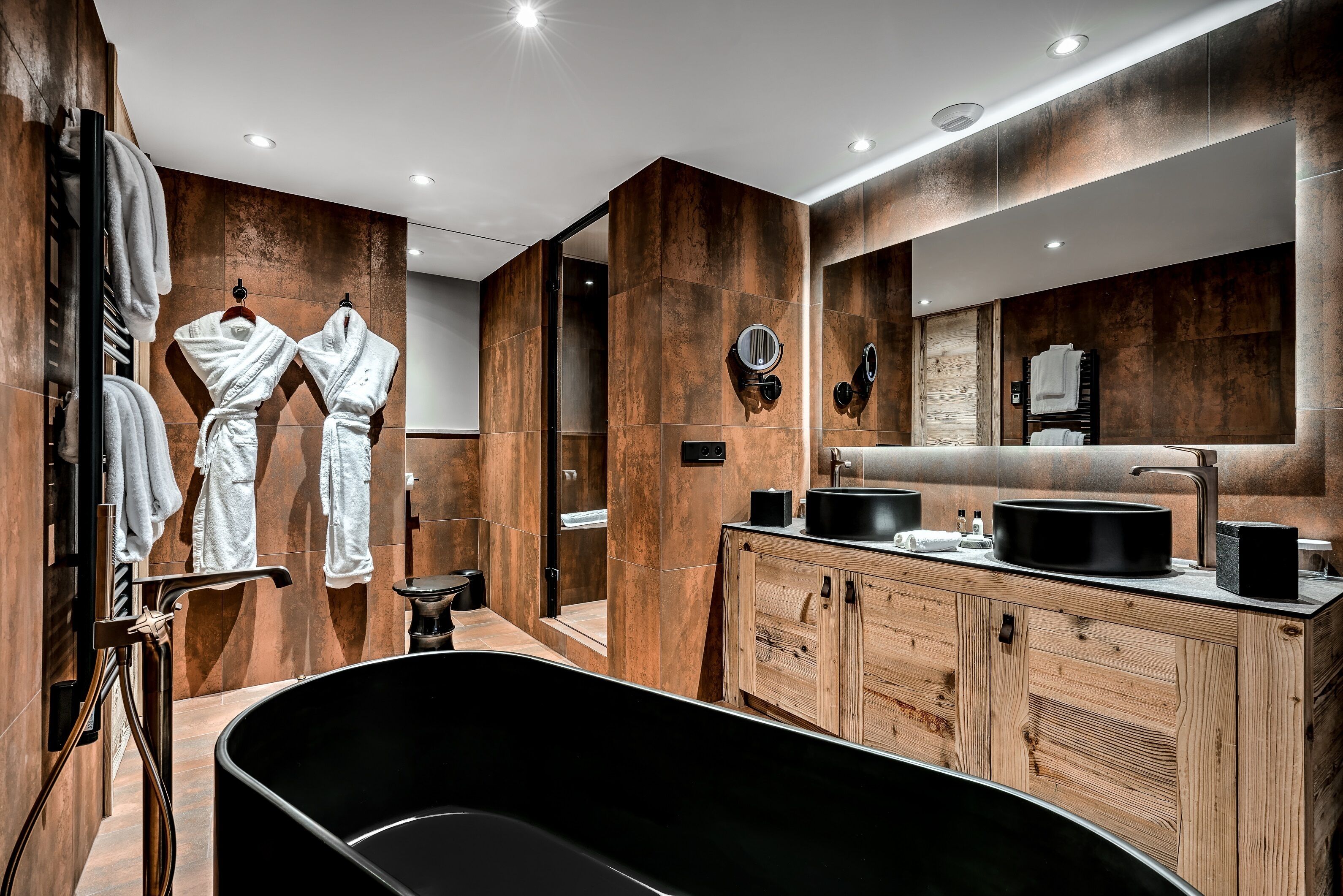 Un baño moderno con una bañera independiente, muebles de madera y un espejo grande.