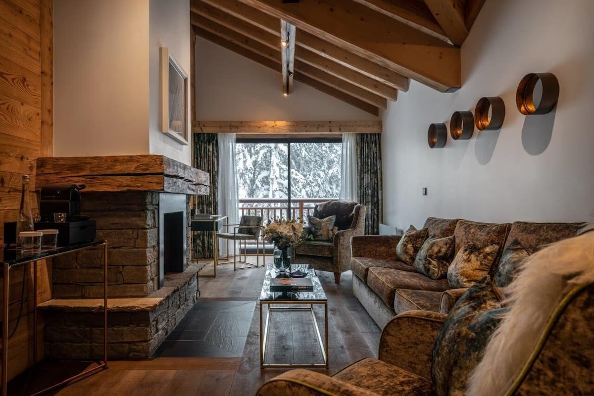 Una sala de estar acogedora con chimenea de piedra, vigas de madera, un sofá y una mesa de centro.