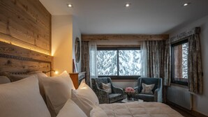 A cozy bedroom with a large bed, a chair, and a window with a snowy view. - Sivolière Hôtel & Résidence (Courchevel)