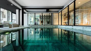 Relax in a serene pool area with a seating space and glass windows offering views of the surrounding area.