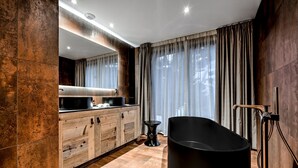 Un baño moderno con una bañera independiente, muebles de madera y un espejo grande.