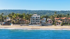 A beachfront hotel with multiple buildings, palm trees, and a view of the ocean. - Watermark Luxury Oceanfront All Suite Hotel (Cabarete)