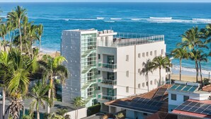 A modern building with a glass facade overlooking a beach and ocean. - Watermark Luxury Oceanfront All Suite Hotel (Cabarete)