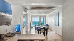 A modern kitchen with a large island, a dining area with a view of the ocean, and a spacious living area with a large window overlooking the sea. - Watermark Luxury Oceanfront All Suite Hotel (Cabarete)