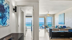 A modern interior with a view of the ocean, a dining area, and a living space with a sofa and coffee table. - Watermark Luxury Oceanfront All Suite Hotel (Cabarete)