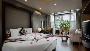A hotel room with a large bed, a TV, a desk, and a view of the city through large windows. - Splendid Star Grand Hotel & Spa (Hanoi)