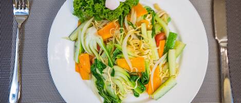 Un plato de fideos con verduras sobre un plato blanco.