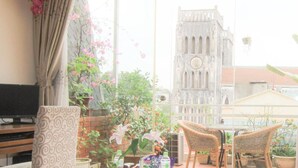 A balcony with wicker chairs, a TV, and potted plants. - Splendid Star Grand Hotel & Spa (Hanoi)
