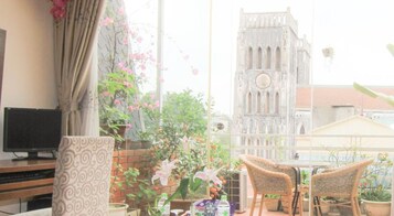 A balcony with wicker chairs, a TV, and potted plants.
