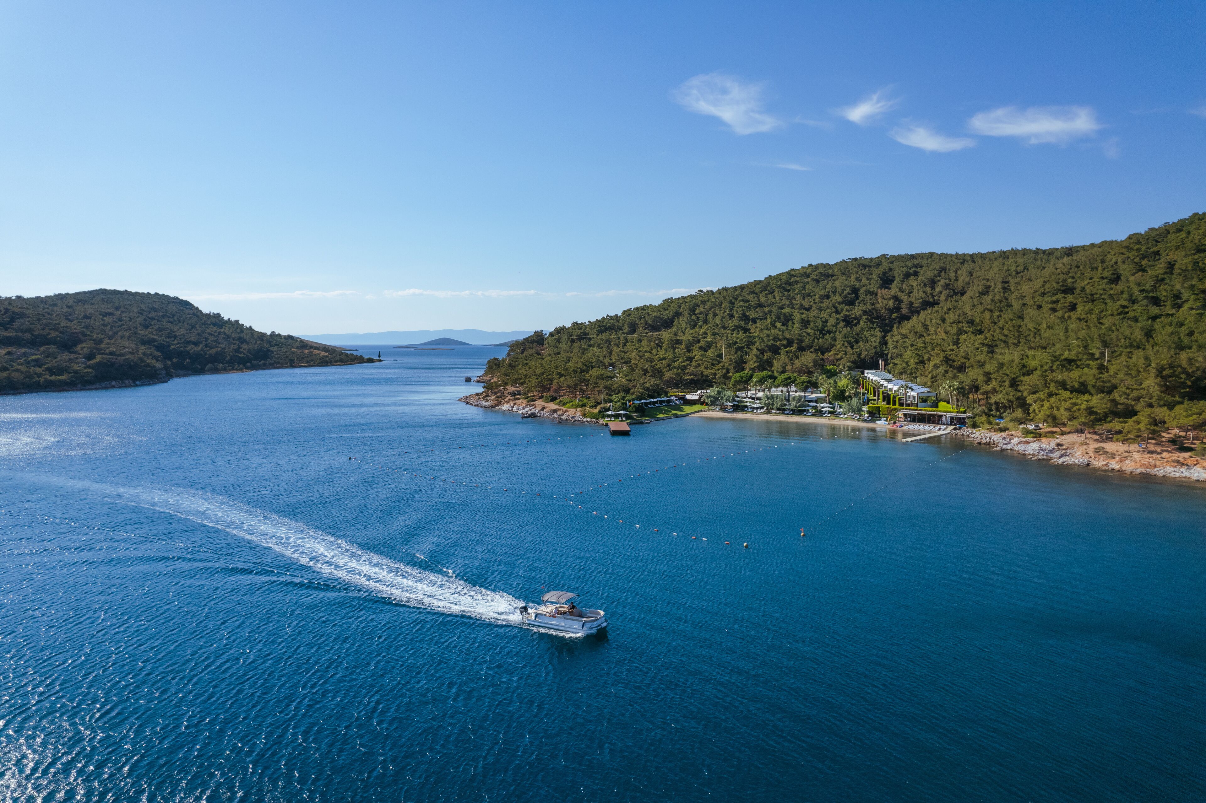 Un bateau navigue sur une étendue d’eau importante, avec une île boisée sur sa droite.