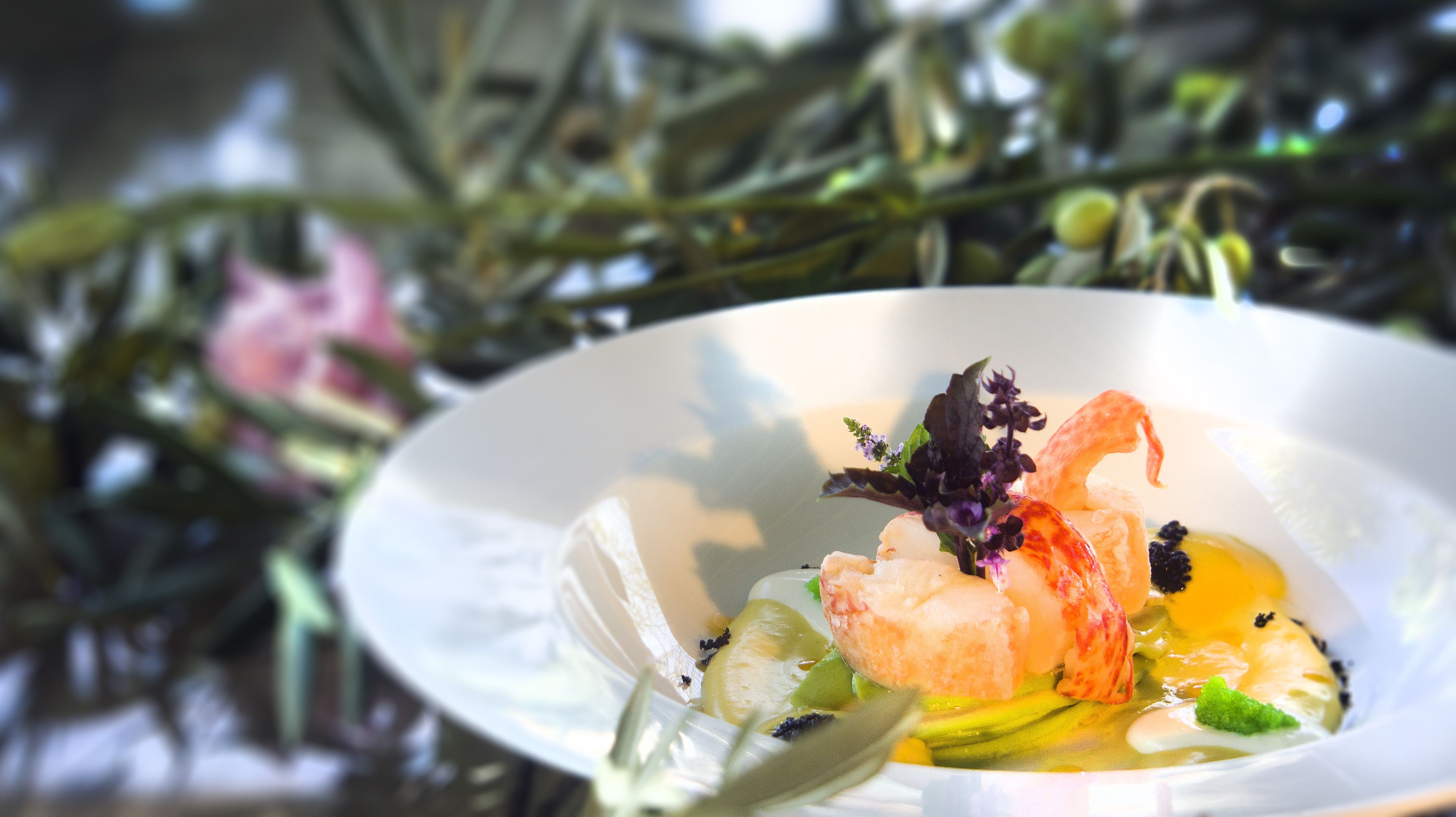 Un plato de mariscos con camarones, vieiras y salsa, adornado con hierbas.