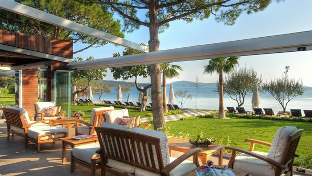 Un área de estar al aire libre, moderna, con mobiliario de madera y vistas al mar.