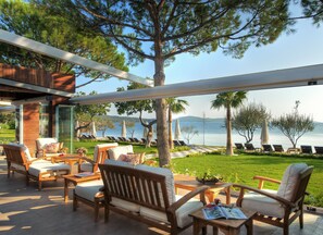 A modern outdoor seating area with wooden furniture and a view of the sea. - Ortunc Hotel - Boutique Class (Ayvalik)
