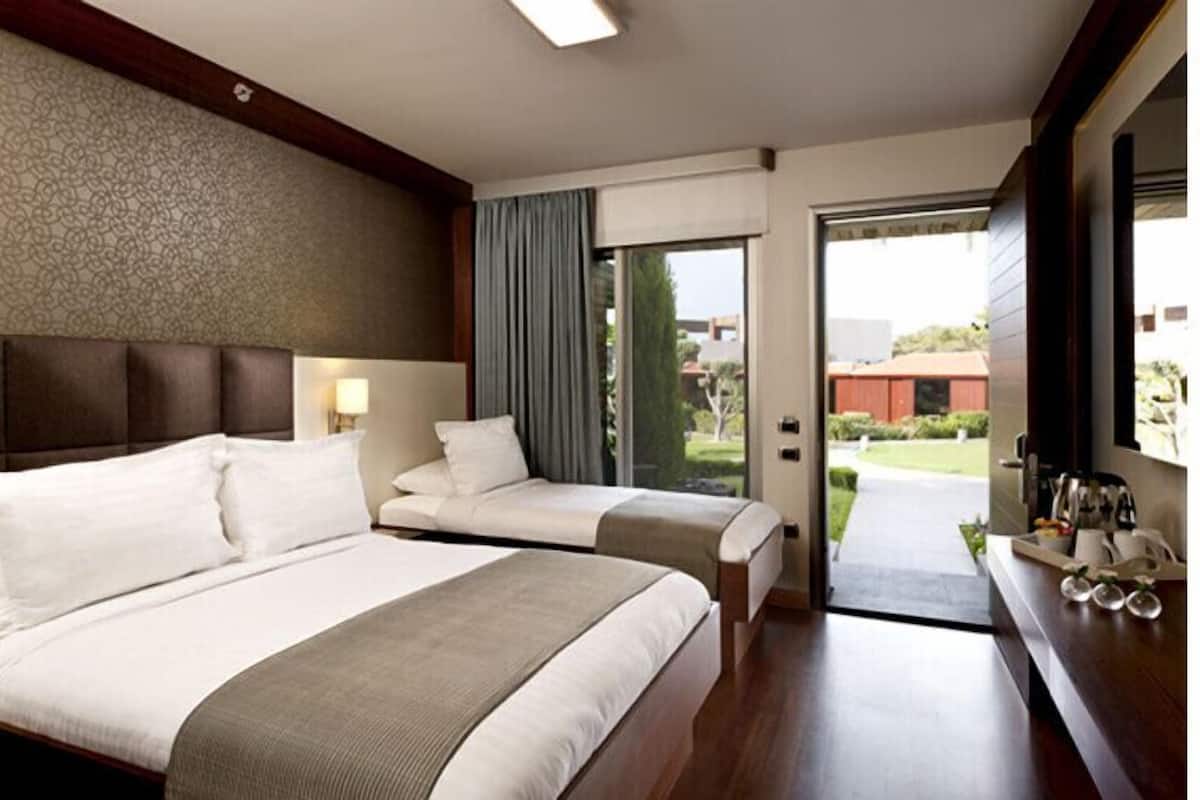 Habitación de hotel con dos camas, un ventanal grande y vistas al exterior.