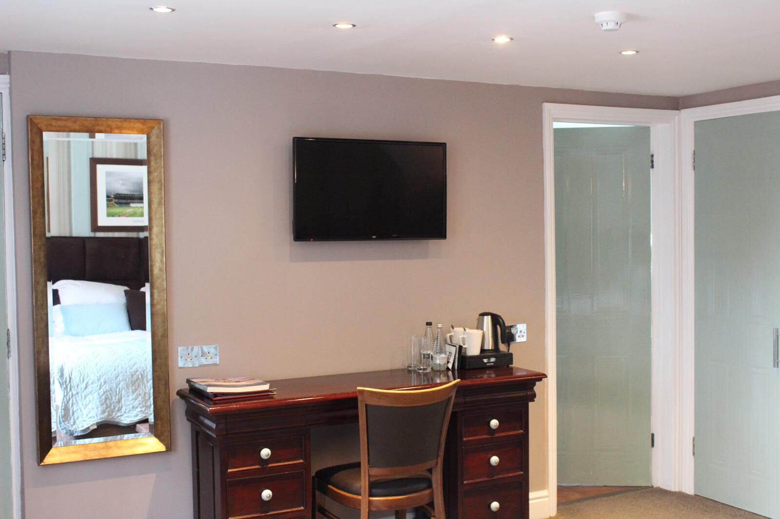 A hotel room with a bed, a desk with a chair, a television, and a door.