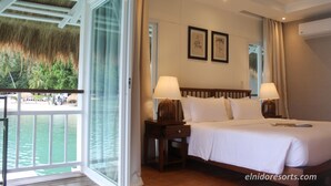 Una habitación de hotel con una cama, dos lámparas de noche, una mesita de noche y vista al océano.