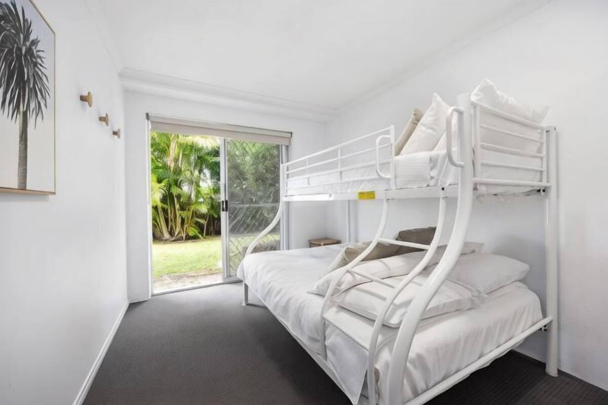 Habitación con literas y una puerta corrediza de vidrio que da a un jardín.